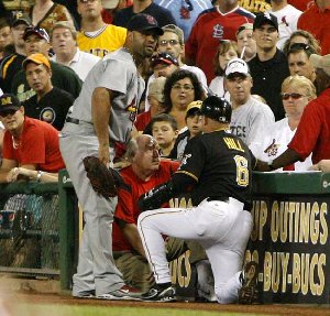 Pittsburgh Pirates first base coach Perry Hill (8) and Cardinals first baseman Albert Pujols (left) come to the aid of a fan who tried to retrieve a foul ball during the seventh inning of a game in Pittsburgh.